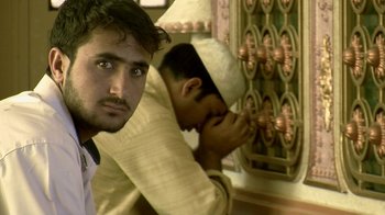 Movie still from “Cameraperson” (2016), directed by Kirsten Johnson – A man looking at the camera while another man looks at the camera; Close Up shot, Low angle