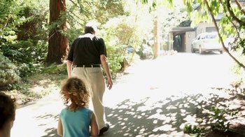 Movie still from “Cameraperson” (2016), directed by Kirsten Johnson – A man and a little girl walking down a sidewalk; Medium shot, Over the shoulder angle