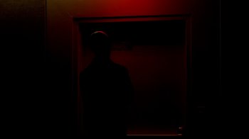 Movie still from “Cameraperson” (2016), directed by Kirsten Johnson – A man standing in a dark room in front of a window; Wide shot, Low angle