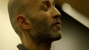 Movie still from “Cameraperson” (2016), directed by Kirsten Johnson – A man with a beard is looking up at the sky; Extreme Close Up shot, Low angle