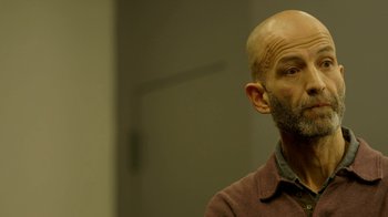 Movie still from “Cameraperson” (2016), directed by Kirsten Johnson – A man with a bald head looking to his left; Close Up shot, Low angle