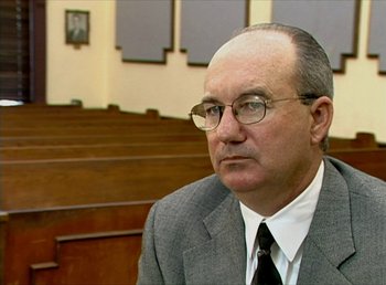 Movie still from “Cameraperson” (2016), directed by Kirsten Johnson – An older man wearing glasses and a suit and tie; Close Up shot, High angle