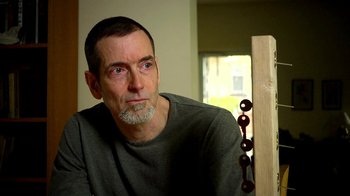 Movie still from “Cameraperson” (2016), directed by Kirsten Johnson – A person sitting in a room near a window; Close Up shot, Low angle