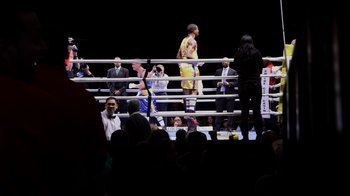 Movie still from “Cameraperson” (2016), directed by Kirsten Johnson – A boxing ring filled with people watching a fight; Wide shot, Over the shoulder angle