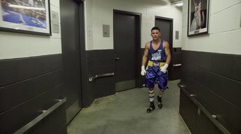 Movie still from “Cameraperson” (2016), directed by Kirsten Johnson – A man in a boxing outfit is walking in a hallway; Wide shot, Overhead angle