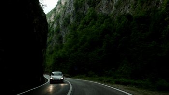 Movie still from “Cameraperson” (2016), directed by Kirsten Johnson – A car driving down a curvy road in the mountains; Extreme Wide shot, High angle