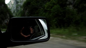 Movie still from “Cameraperson” (2016), directed by Kirsten Johnson – A person's hand in a rear view mirror of a car; Close Up shot, Low angle