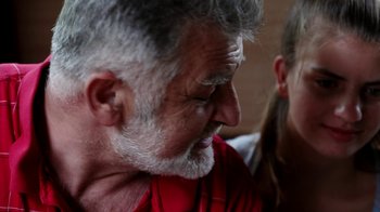 Movie still from “Cameraperson” (2016), directed by Kirsten Johnson – An older man and a younger woman sitting next to each other; Close Up shot, Over the shoulder angle