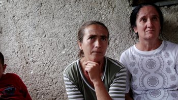 Movie still from “Cameraperson” (2016), directed by Kirsten Johnson – A woman sitting next to another woman in front of a wall; Close Up shot, High angle