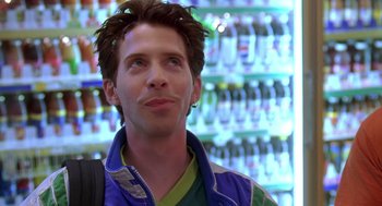 Movie still from “Can't Hardly Wait” (1998), directed by Deborah Kaplan – A young man standing in front of a wall of bottles; Close Up shot, Low angle