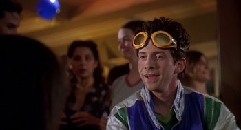 Movie still from “Can't Hardly Wait” (1998), directed by Deborah Kaplan – A young man wearing goggles and smiling for the camera; Close Up shot, Over the shoulder angle