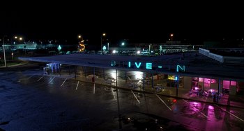Movie still from “Can't Hardly Wait” (1998), directed by Deborah Kaplan – An empty parking lot at night with neon lights; Extreme Wide shot, High angle