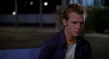 Movie still from “Can't Hardly Wait” (1998), directed by Deborah Kaplan – A man sitting on top of a bench in a parking lot; Close Up shot, Over the shoulder angle