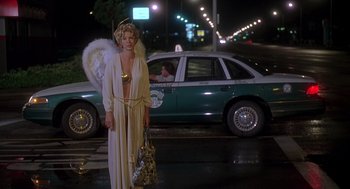 Movie still from “Can't Hardly Wait” (1998), directed by Deborah Kaplan – A woman dressed as an angel standing in front of a taxi cab; Wide shot, Low angle