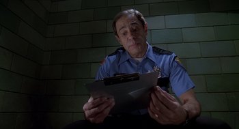 Movie still from “Can't Hardly Wait” (1998), directed by Deborah Kaplan – A police officer sitting in front of a clipboard; Close Up shot, Low angle