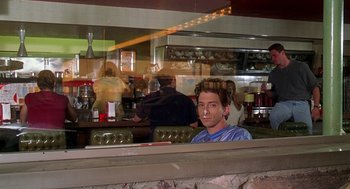 Movie still from “Can't Hardly Wait” (1998), directed by Deborah Kaplan – A man sitting at a counter in a restaurant; Medium shot, Over the shoulder angle