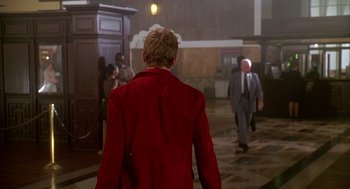 Movie still from “Can't Hardly Wait” (1998), directed by Deborah Kaplan – A man in a red coat walking in a hallway; Wide shot, Over the shoulder angle
