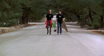 Movie still from “Can't Hardly Wait” (1998), directed by Deborah Kaplan – Two people walking down a street holding bags; Wide shot, Low angle
