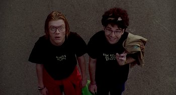 Movie still from “Can't Hardly Wait” (1998), directed by Deborah Kaplan – A couple of people standing next to each other on the street; Medium shot, Overhead angle