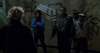 Movie still from “Candyman” (1992), directed by Bernard Rose – A group of men standing next to each other in front of a wall; Medium shot, Over the shoulder angle