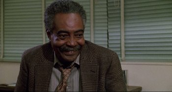 Movie still from “Candyman” (1992), directed by Bernard Rose – An older man wearing a suit and smiling; Close Up shot, Low angle