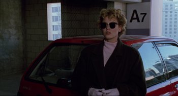 Movie still from “Candyman” (1992), directed by Bernard Rose – A woman wearing sunglasses standing in front of a car; Medium shot, Low angle