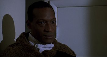 Movie still from “Candyman” (1992), directed by Bernard Rose – A man wearing a brown coat and a white bow tie; Close Up shot, Low angle