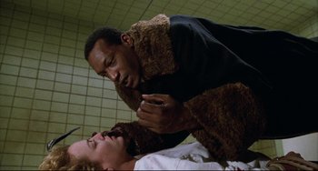 Movie still from “Candyman” (1992), directed by Bernard Rose – A man in a brown jacket is standing over another man in a white shirt; Medium shot, Low angle