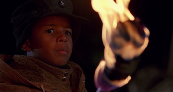 Movie still from “Candyman” (1992), directed by Bernard Rose – A young boy in a cowboy hat looks at the flame of a fire; Close Up shot, Low angle