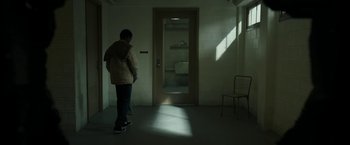 Movie still from “Candyman” (2021), directed by Nia DaCosta – A person standing in a room with a door open; Wide shot, High angle