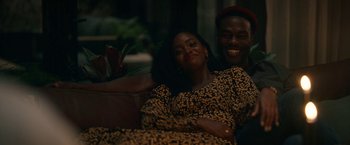 Movie still from “Candyman” (2021), directed by Nia DaCosta – A man and a woman sitting on top of a couch; Medium shot, High angle