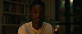 Movie still from “Candyman” (2021), directed by Nia DaCosta – A person wearing a white t - shirt; Close Up shot, Over the shoulder angle