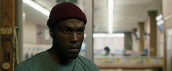 Movie still from “Candyman” (2021), directed by Nia DaCosta – A person wearing a hat; Close Up shot, Over the shoulder angle