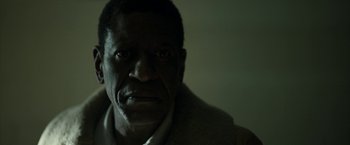 Movie still from “Candyman” (2021), directed by Nia DaCosta – A man's face in a dark room; Close Up shot, Low angle