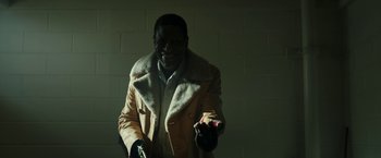 Movie still from “Candyman” (2021), directed by Nia DaCosta – A man wearing a coat is holding something in his hand; Medium shot, Over the shoulder angle