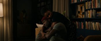 Movie still from “Candyman” (2021), directed by Nia DaCosta – A man and a woman sitting next to each other on a couch; Medium shot, High angle