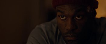 Movie still from “Candyman” (2021), directed by Nia DaCosta – A person wearing a hat; Close Up shot, High angle