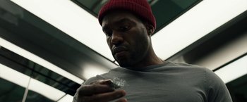 Movie still from “Candyman” (2021), directed by Nia DaCosta – A person holding something in his hand; Close Up shot, Low angle