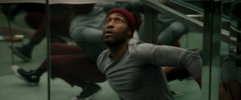 Movie still from “Candyman” (2021), directed by Nia DaCosta – A man with a red hat is looking up; Close Up shot, Overhead angle