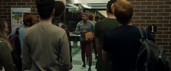 Movie still from “Candyman” (2021), directed by Nia DaCosta – A group of people standing in a room; Medium shot, Over the shoulder angle