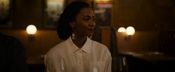 Movie still from “Candyman” (2021), directed by Nia DaCosta – A woman wearing a white shirt and a pair of earrings; Close Up shot, Over the shoulder angle
