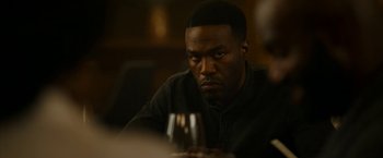 Movie still from “Candyman” (2021), directed by Nia DaCosta – A man sitting in front of a glass of wine; Close Up shot, Over the shoulder angle