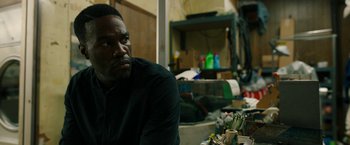Movie still from “Candyman” (2021), directed by Nia DaCosta – A man sitting in front of a pile of garbage; Close Up shot, Over the shoulder angle