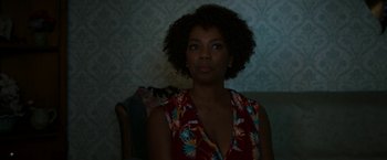 Movie still from “Candyman” (2021), directed by Nia DaCosta – A woman sitting on a couch in the dark; Close Up shot, Over the shoulder angle