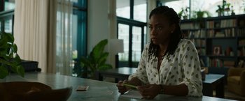 Movie still from “Candyman” (2021), directed by Nia DaCosta – A woman sitting at a table writing on a piece of paper; Medium shot, Over the shoulder angle