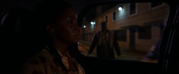 Movie still from “Candyman” (2021), directed by Nia DaCosta – A woman sitting in the back seat of a car at night; Close Up shot, Over the shoulder angle