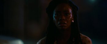 Movie still from “Candyman” (2021), directed by Nia DaCosta – A woman with dreadlocks is looking at the camera; Close Up shot, Over the shoulder angle