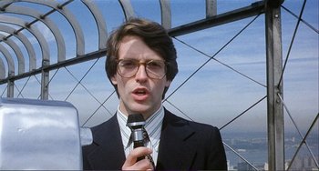 Movie still from “Cannibal Holocaust” (1980), directed by Ruggero Deodato – A man in a suit and glasses is holding a microphone; Close Up shot, Low angle
