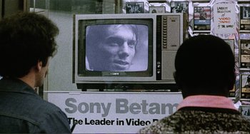 Movie still from “Cannibal Holocaust” (1980), directed by Ruggero Deodato – A television set with a man's face on the screen; Extreme Close Up shot, Over the shoulder angle