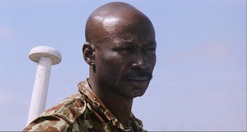 Movie still from “Cannibal Holocaust” (1980), directed by Ruggero Deodato – A person wearing a camouflage uniform; Close Up shot, Low angle